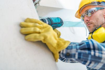 Low angle view of mid adult man drilling wall in house