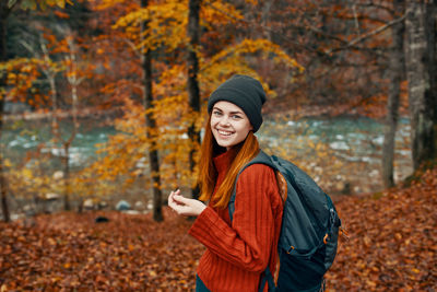 Portrait of smiling young man in forest during autumn