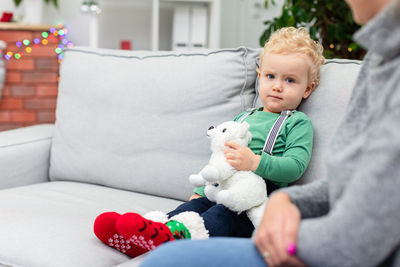 High angle view of mother and daughter sitting on sofa at home