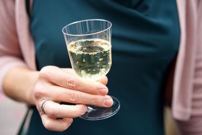 Cropped hand holding plastic cup with wine