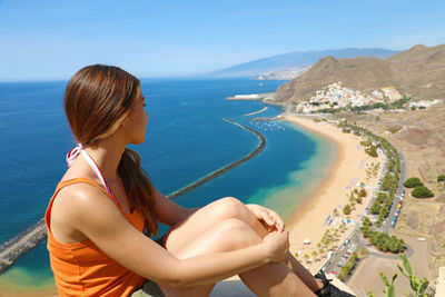 Woman looking at sea by mountain