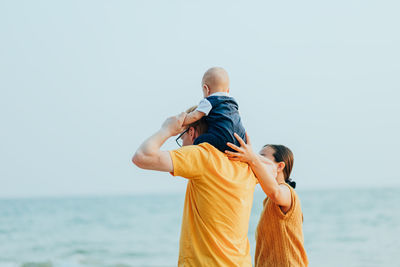 Woman standing with man carrying son on shoulders