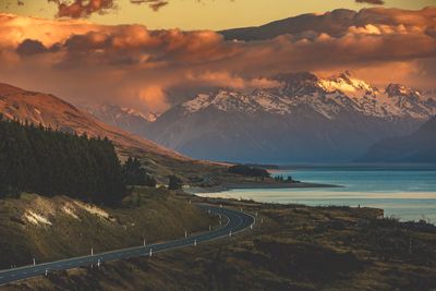 Winding road passing through mountains against dramatic sky