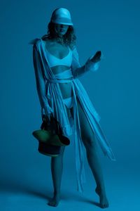 Full length of woman standing against blue background