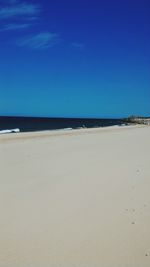 Scenic view of beach against clear blue sky