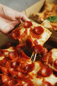 Close-up of hand holding pizza