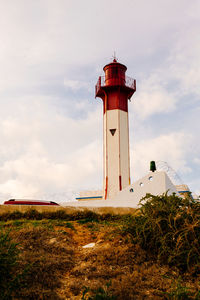 Lighthouse by street amidst buildings against sky