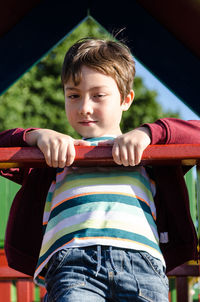 Portrait of boy hanging from pole at playground