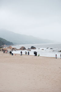 People at beach against clear sky