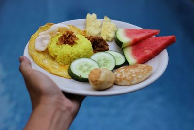 Close-up of hand holding meal in plate