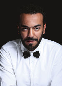 Portrait of young man against black background