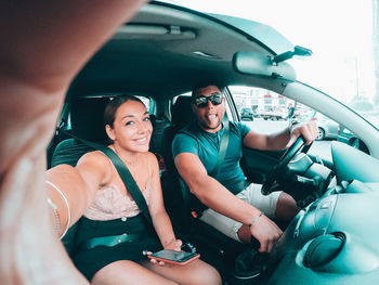 Portrait of smiling young woman doing selfie while sitting in car