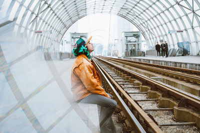 Side view of man sitting at railroad station platform