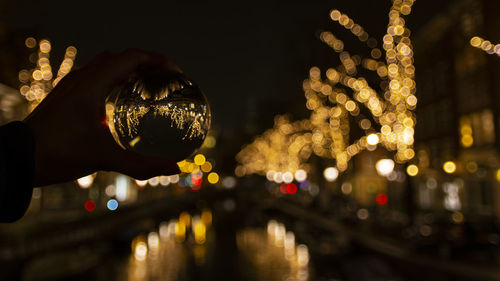 Close-up of person holding illuminated christmas lights at night