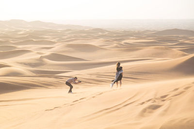 Man photographing woman standing at desert