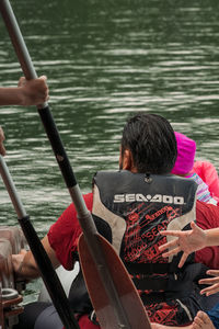 Rear view of people sitting on boat in river