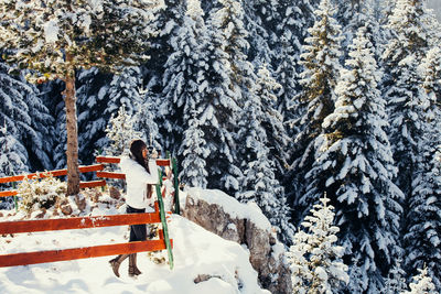 Woman drinking tea while standing on snow covered mountain