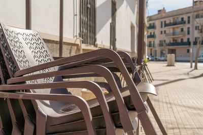 Empty chairs and tables on street against buildings in city