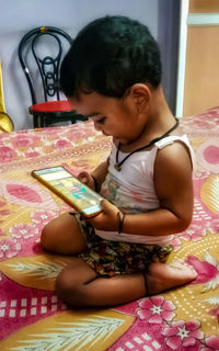 Full length of girl sitting on bed