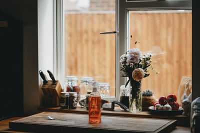 Flower vase with spices on window sill at home