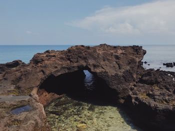 Rock formation on beach against sky