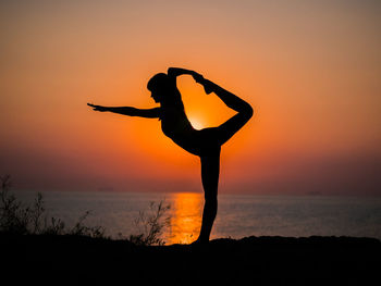 Silhouette woman standing by sea against sky during sunset