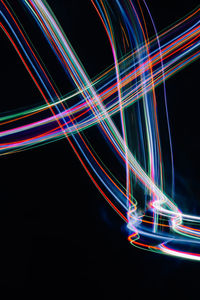 Light trails against illuminated lights over black background