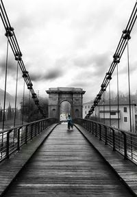 Pier on river against cloudy sky