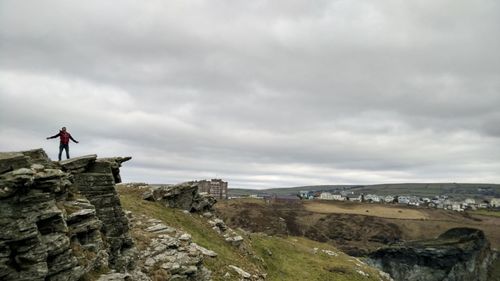 Man standing on cliff against sky