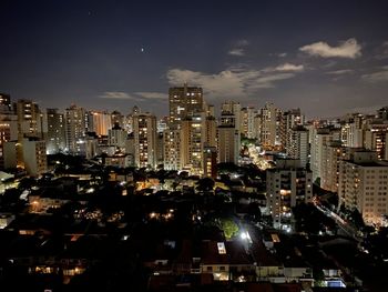 Illuminated buildings in city against sky at night