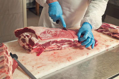 Cropped image of man cutting beef at table