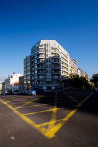 Road by buildings against blue sky