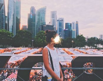 Digital composite image of firework exploding on woman face in city during event