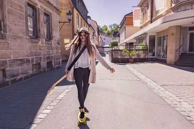 Portrait of teenage girl skateboarding on footpath