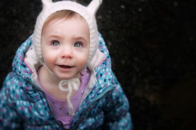 Close-up portrait of baby girl in warm clothes over back background