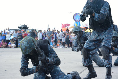 Armed forces performing parade on road with people in background