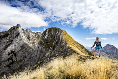 Rear view of woman standing on mountain against sky