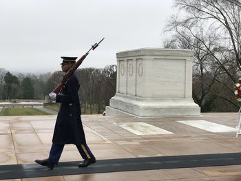 Side view of man holding umbrella against sky