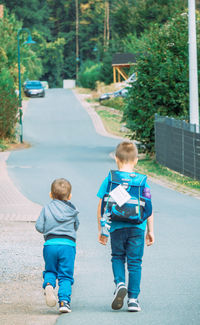 Rear view of boy walking on road