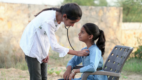 Female doctor or pediatrician with stethoscope listening to heartbeat girl's patient