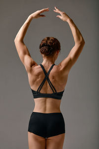 Portrait of young woman exercising against black background