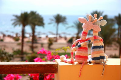 Two crochet giraffes in love  are enjoying their vacation and looking at the sea. 