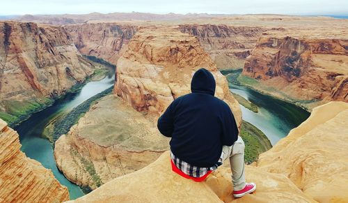 Scenic view of person sitting on rock against mountains