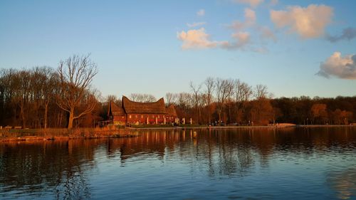 House by lake against sky