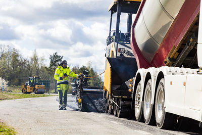 Man standing by asphalt paving machine