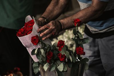 Midsection of man holding bouquet of roses