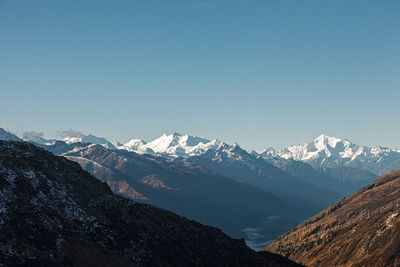 Scenic view of snowcapped mountains against clear blue sky