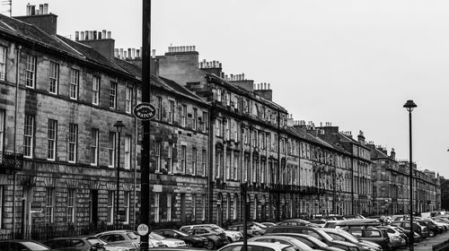 Cars on street by buildings against clear sky