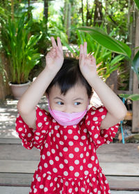 Charming 3 years cute baby asian girl raising her 2 fingers up both hands like rabbit.