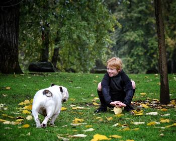 Full length of dog and boy on grassy field